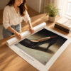 Woman carefully rolling a museum-quality Sole Support fine art print before secure worldwide shipping in a protective mailing tube.