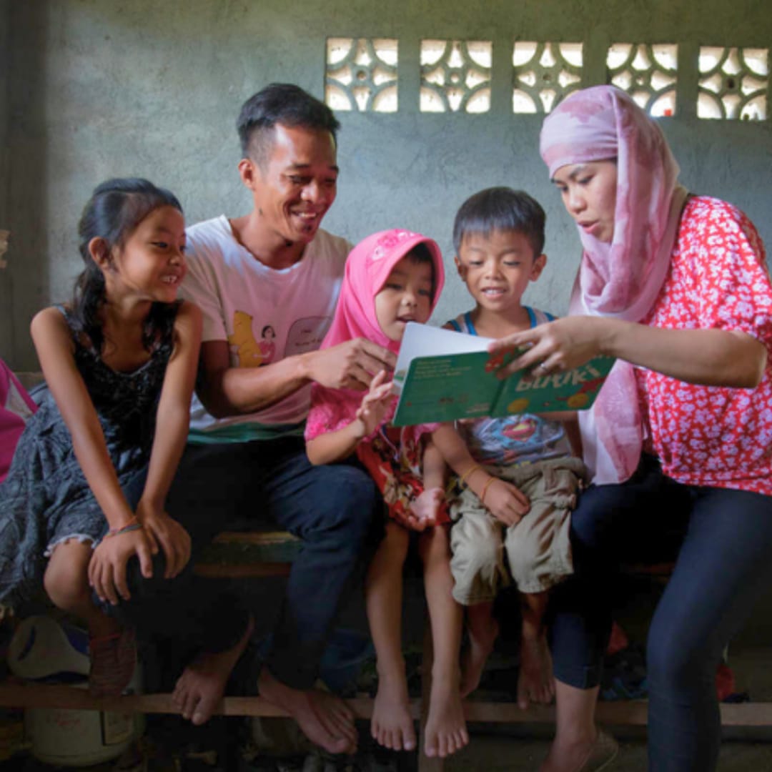 Family with children receiving educational support and reading together in Manila, Philippines.