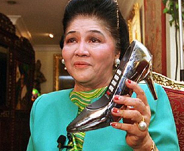 Imelda Marcos holding a silver high-heeled shoe-shaped telephone from her famous shoe collection