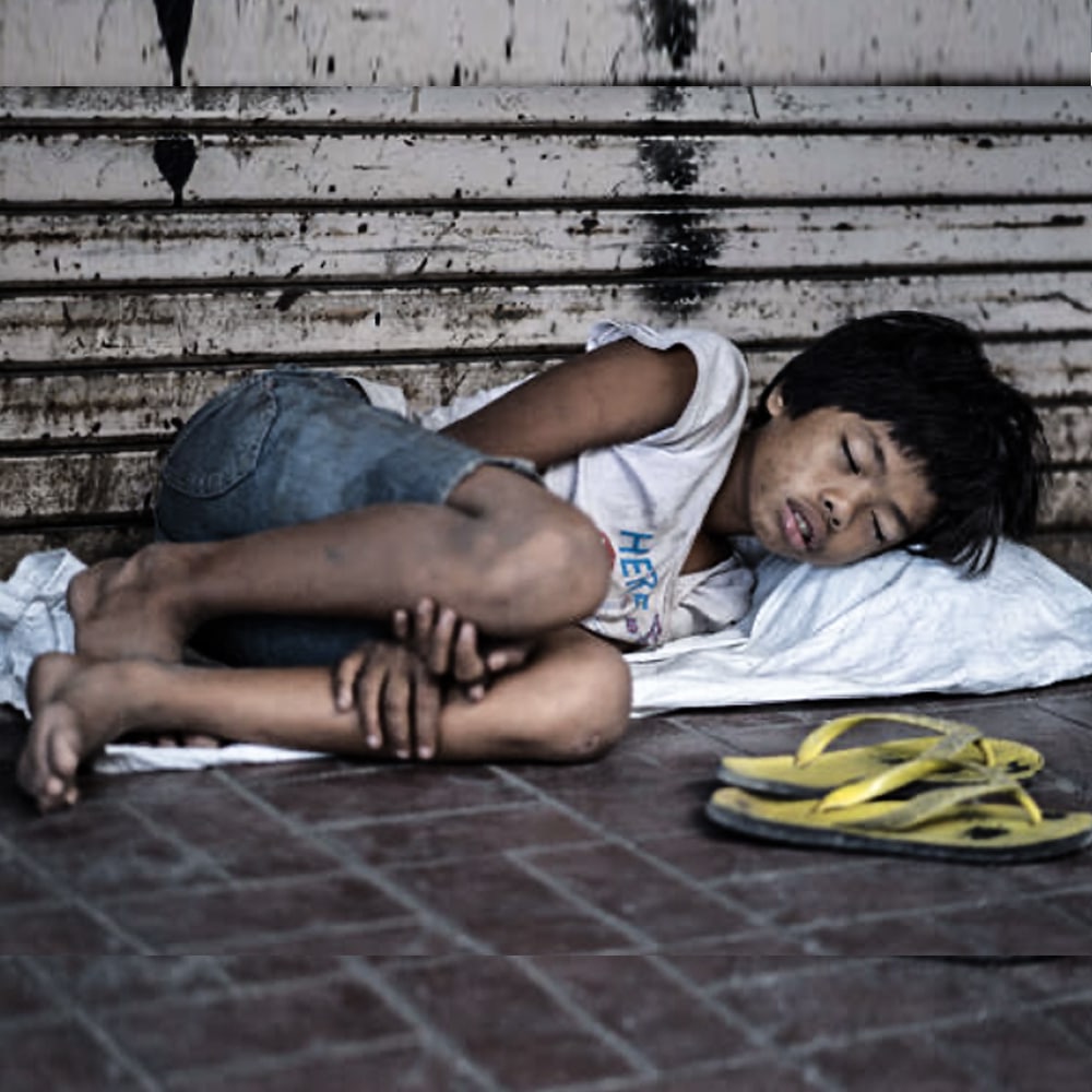 Boy sleeping on the street in Manila, illustrating the hardship faced by vulnerable children living in poverty in the Philippines.