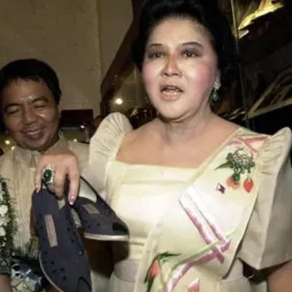Imelda Marcos holding a shoe from her famous shoe collection during a public appearance in the Philippines.