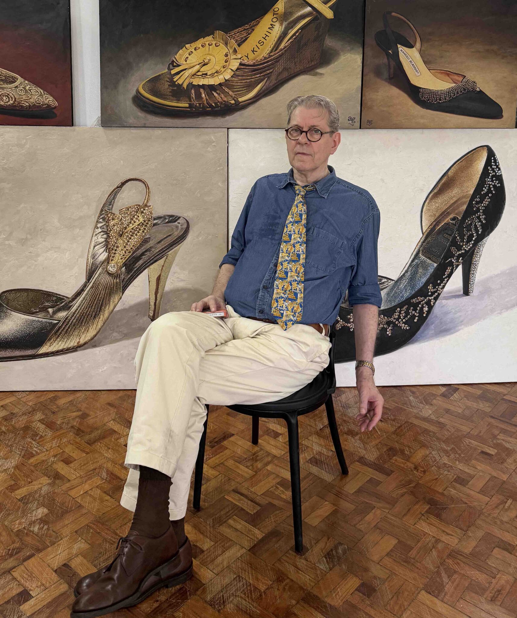 A. J. Green seated among his original paintings of Imelda Marcos shoes
