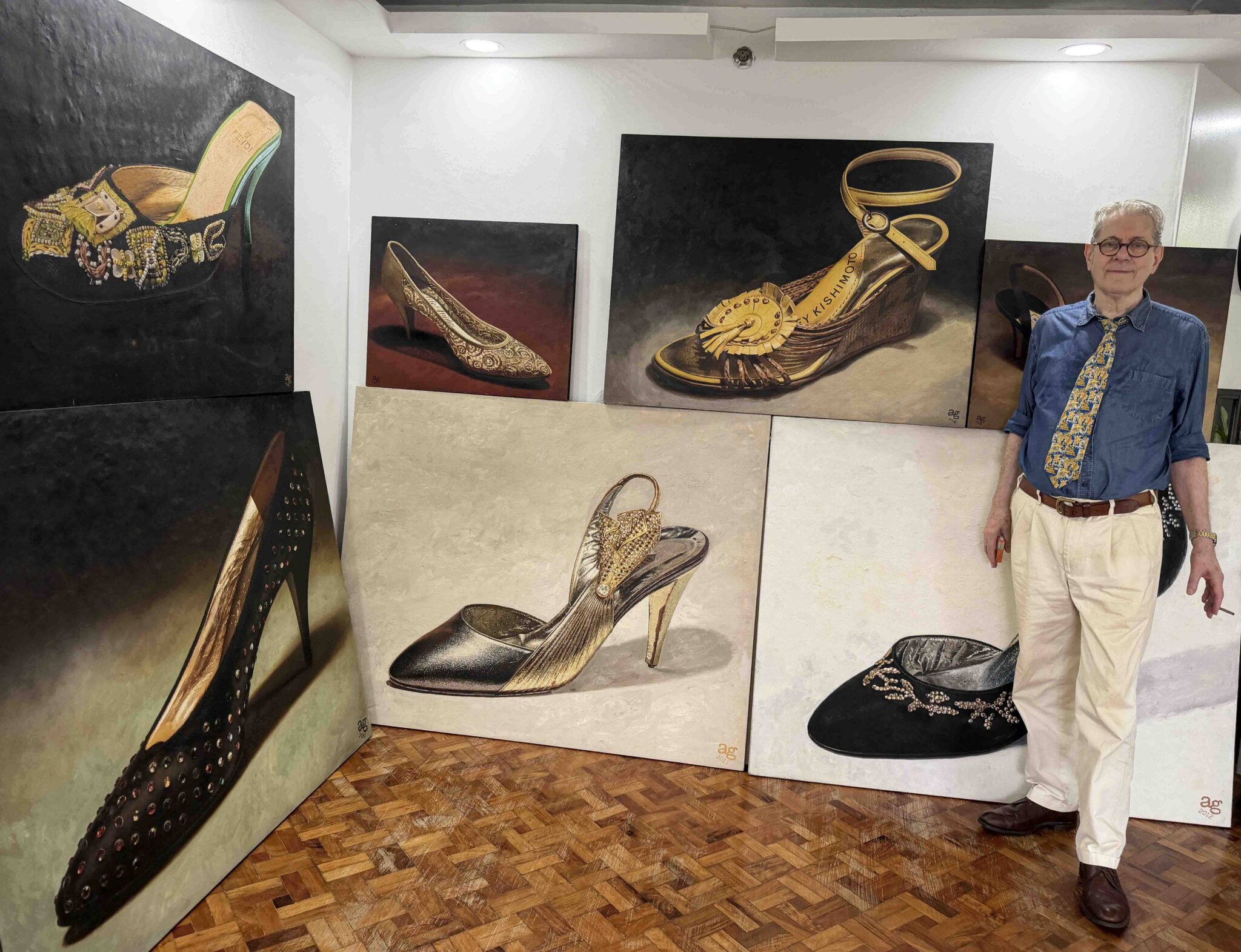 A. J. Green standing surrounded by his original paintings of Imelda Marcos shoes
