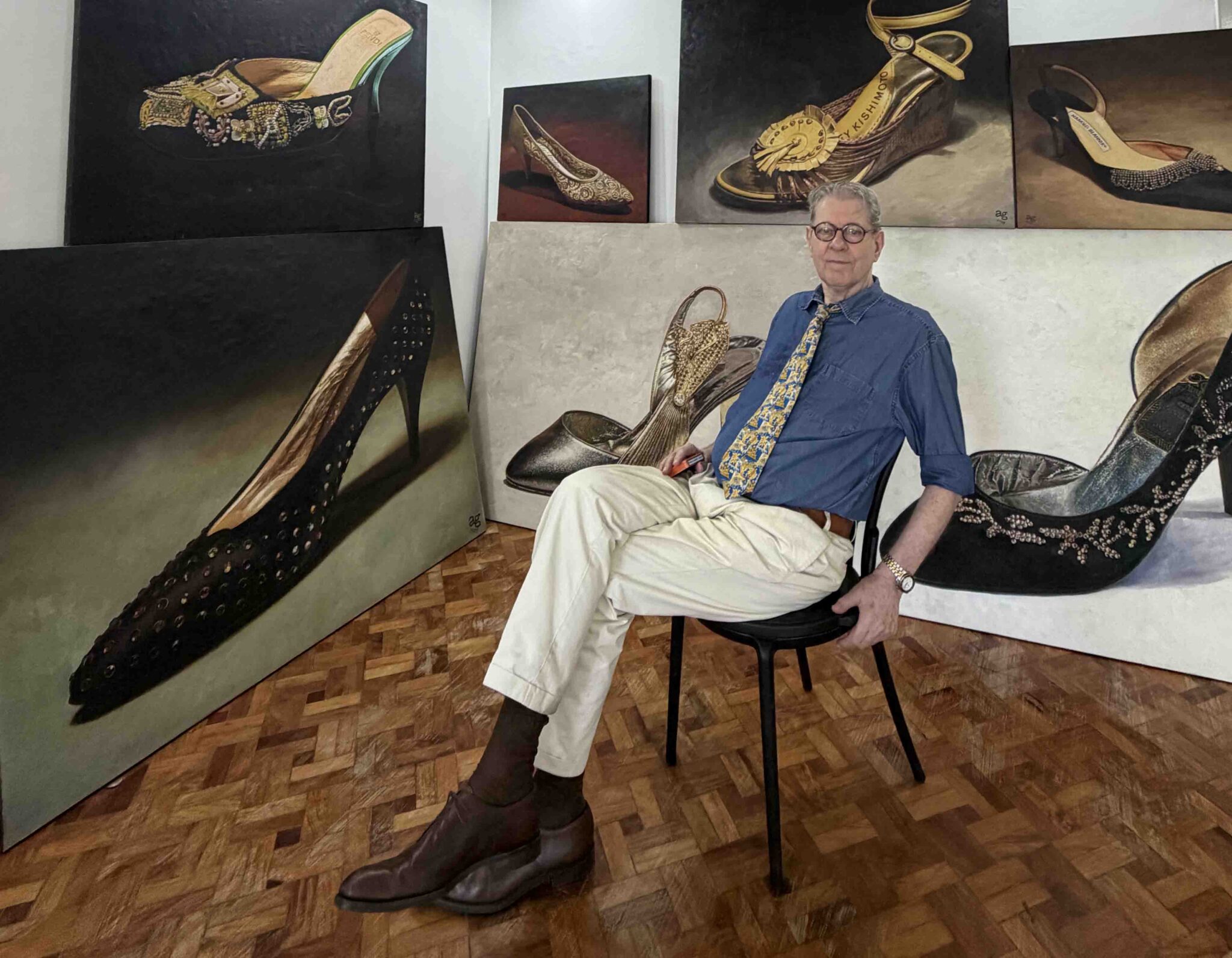 A. J. Green seated among his paintings of shoes from Imelda Marcos's collection